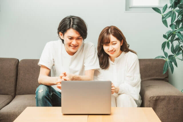 二人でソファに座りパソコンを操作していいるカップル