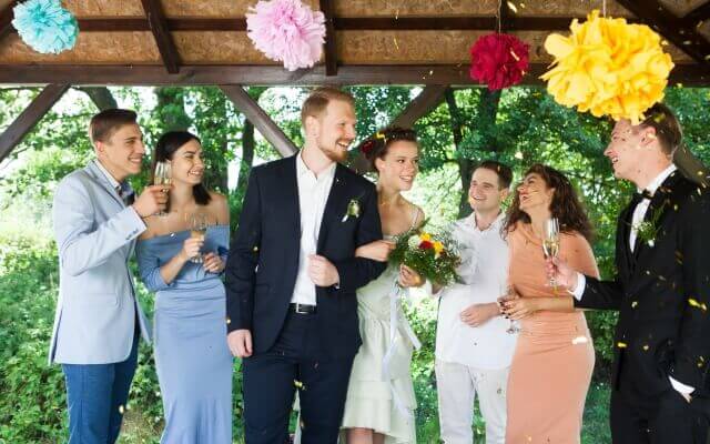 ゲストに囲まれて笑顔で腕組みする新郎新婦