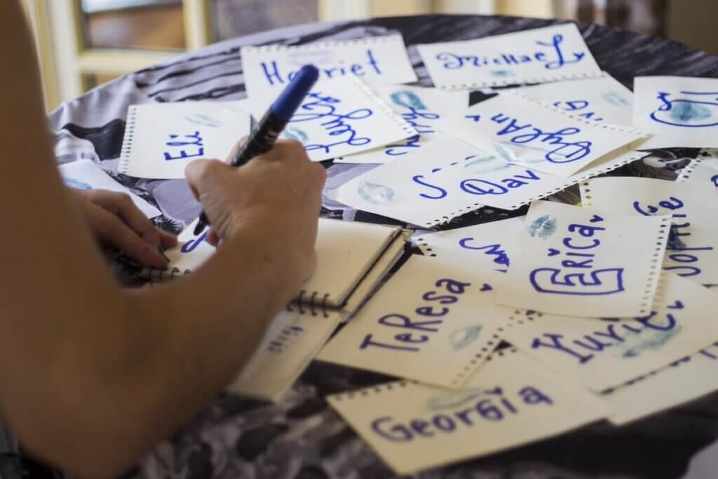 たくさんの紙にマジックで名前を書いている