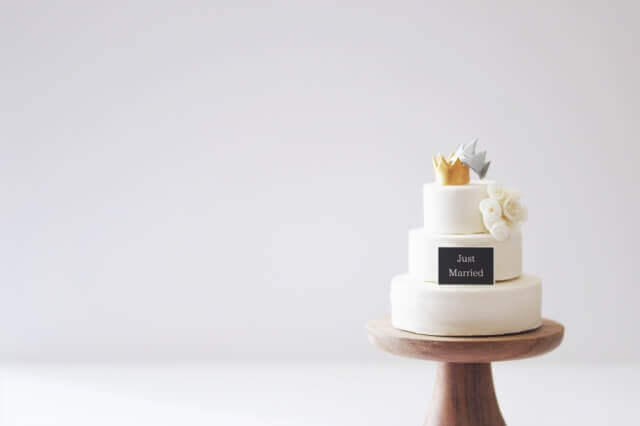 最上段に王冠があしらわれた3段の純白のウェディングケーキ