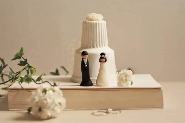 ほんの上に置かれた小さなケーキと新郎新婦の人形