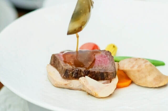 牛フィレ肉のステーキにソースをかけている