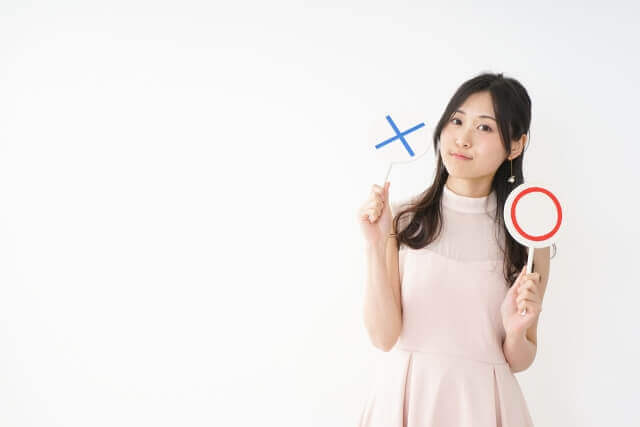 ◯と×の上げ札を持った女性