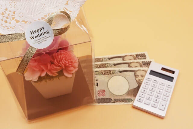 Happy Weddingとパッケージに書かれたギフトと3万円と電卓の写真