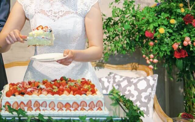 ファーストバイトを行うために、ウェディングケーキを取り分ける新婦
