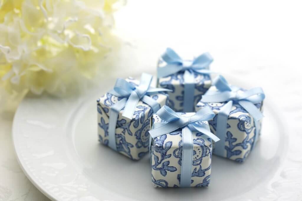 白いお皿の上にある水色のリボンがかけられた4つの小さなギフトボックス