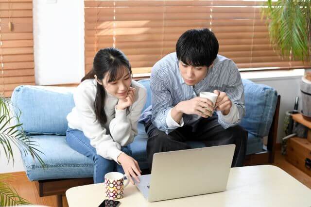 パソコンを覗き込んで、何かを検索するカップル