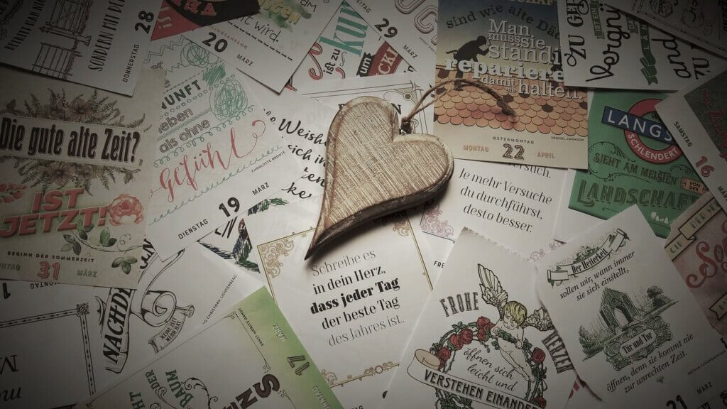 たくさんのヴィンテージ画像の上に木造りのハートの雑貨が置かれている