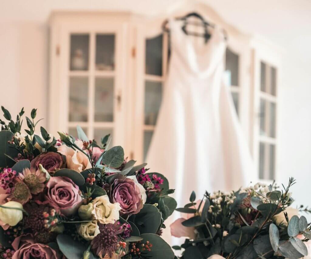 背景に飾られたウェディングドレスと落ち着いたシックな色合いの2つのブーケ