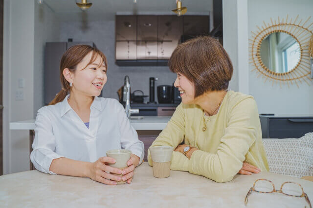 キッチンで飲み物を飲みながら話をする娘と母親