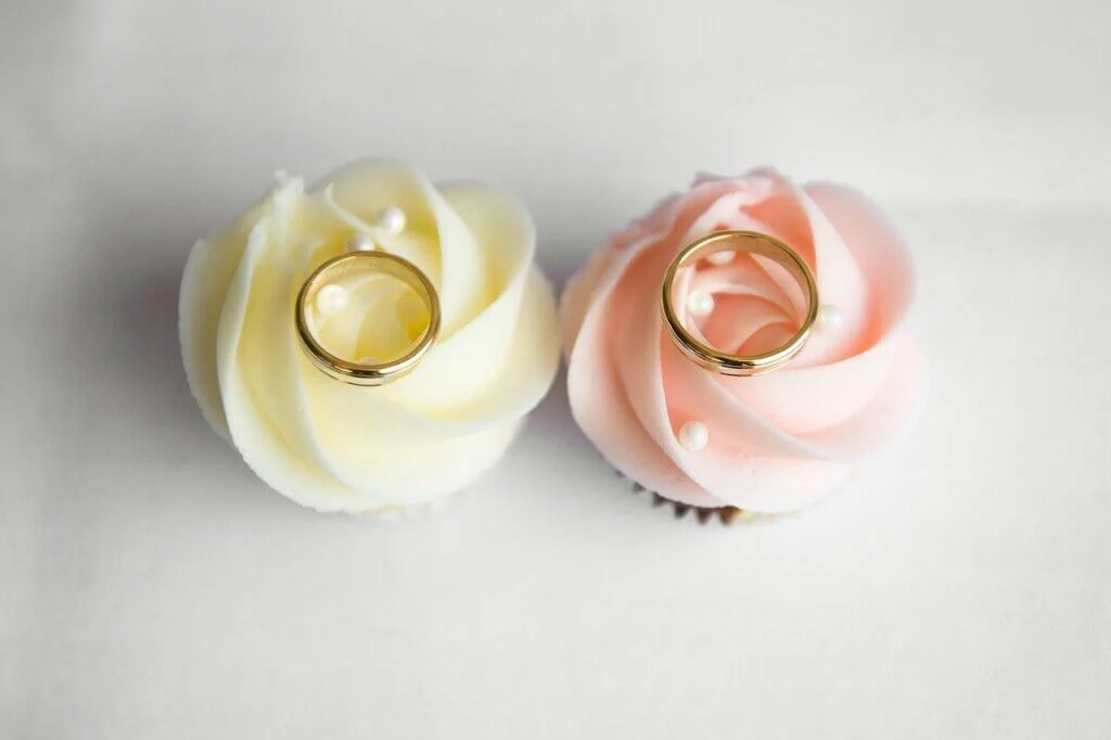 黄色とピンクのバラの上に置かれた一対の結婚指輪