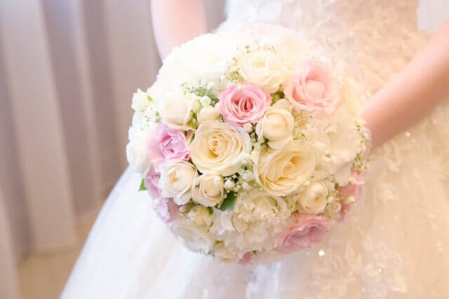 淡い色のブーケを手に持ちウェディングドレス姿の新婦