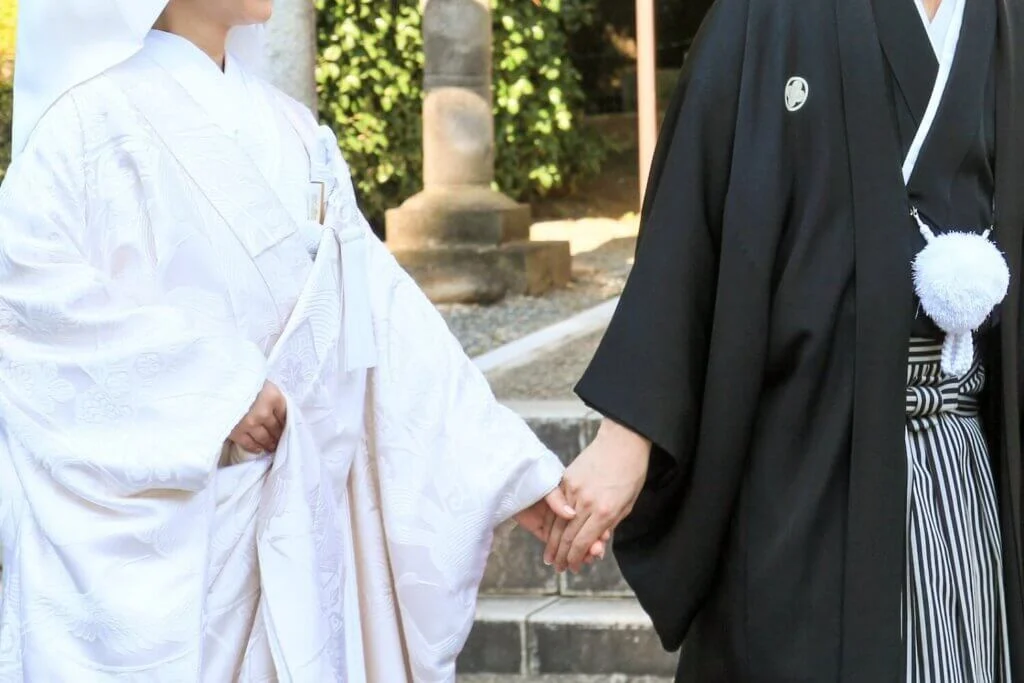 手を取り合って歩く羽織袴姿の新郎と、白無垢姿の新婦