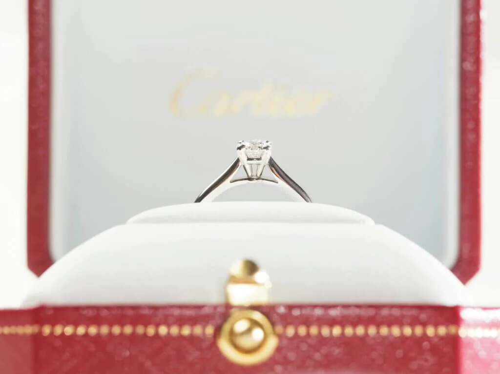 カルチェと書かれた指輪ケースに収められているダイヤモンドの婚約指輪