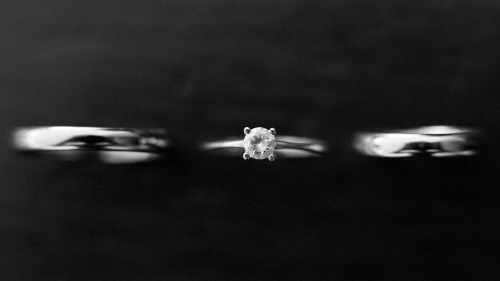 黒い背景の真ん中にダイヤモンドの婚約指輪が表示されている