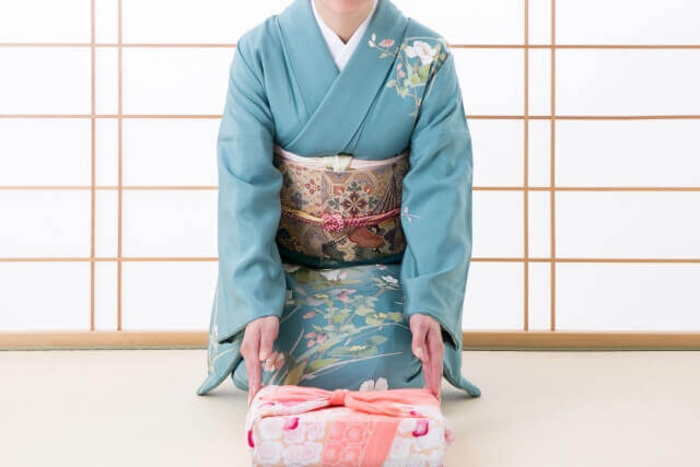和室で贈り物を差し出す和服姿の女性