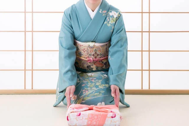 和室で贈り物を差し出す和服姿の女性