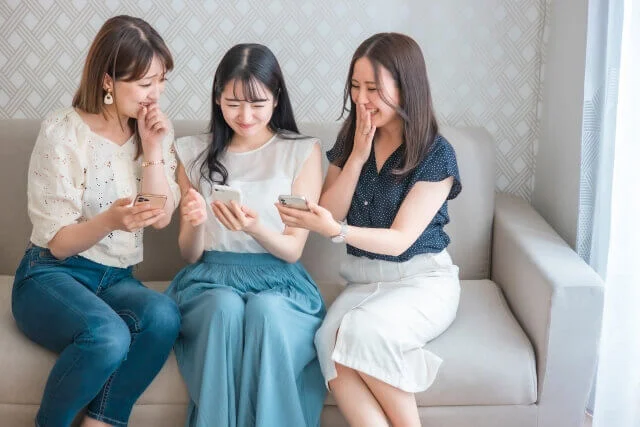 スマホを見て楽しそうに笑っている3人の女性