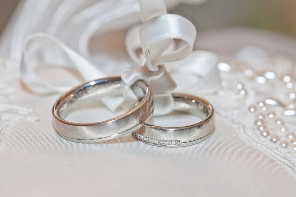 リングピローに上で白いリボンで結ばれた結婚指輪のセット