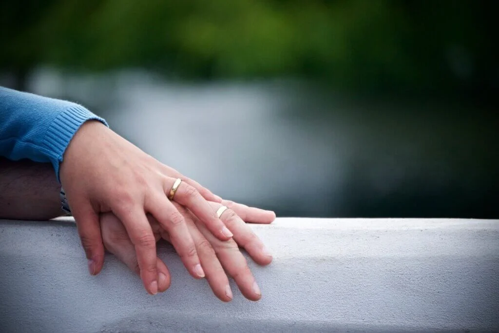 結婚指輪をはめた男女の手が重ねられている