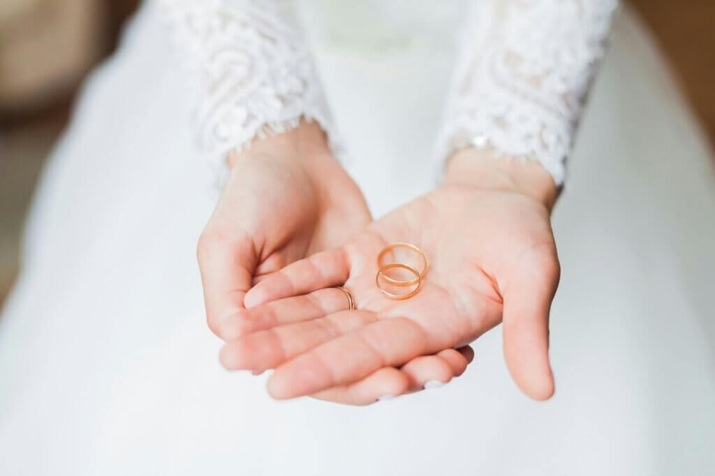 新婦の手のひらに乗せられた金色の結婚指輪セット