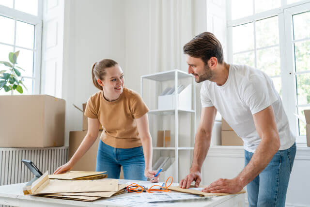 カップルが机の前で力を合わせて事務作業をしている