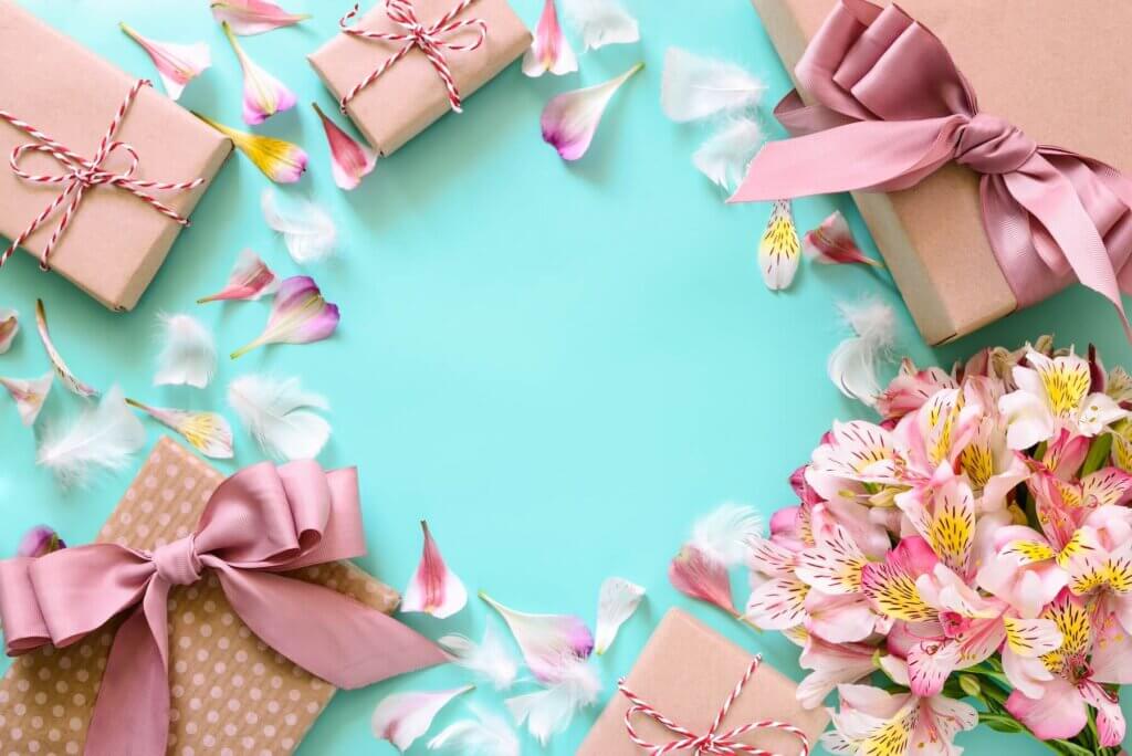 グリーンの背景にたくさんのギフトボックスと花が飾られている