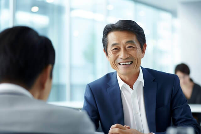 職場で笑顔いっぱいで話し合っている中年の男性