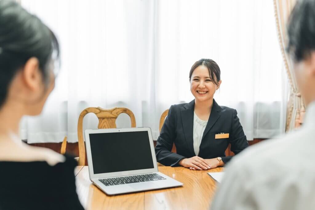 結婚式場を相談カウンターで担当のカウンセラーに式場探しの相談を行っているカップル。