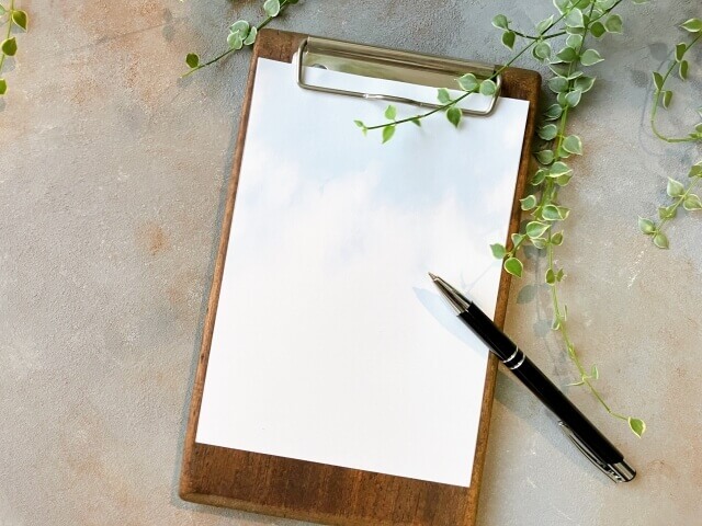 木製のボードに何も書かれていない。白い紙が挟まれており、その上にボールペンが置かれている。
