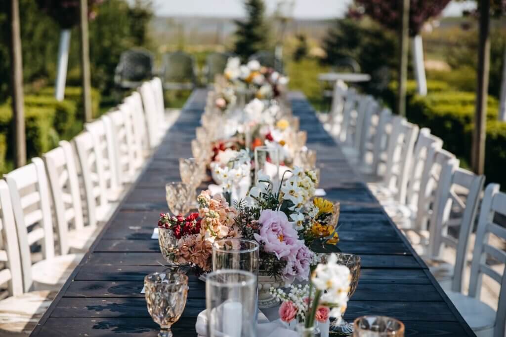 ガーデンウェディングの流しテーブルに飾られた装花。緑いっぱいの背景が美しい。