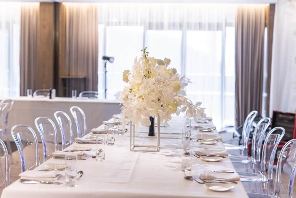 白い披露宴会場に白の端白いテーブルクロス、白いナフキン透明の椅子でコーディネートされている会場