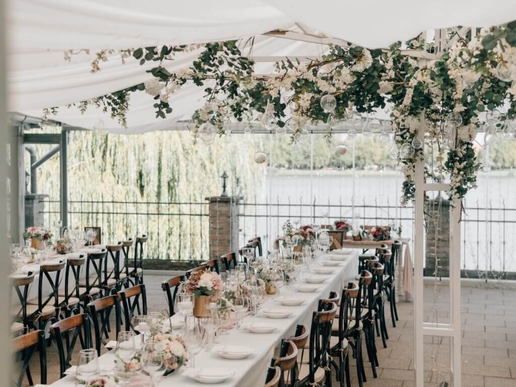 白いテントの下で白のテーブルクロスとナチュラルテイストのたくさんの花と緑で装飾された披露宴会場