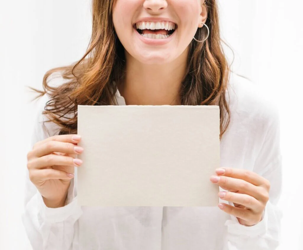 真っ白な紙を両手で持ち、笑顔でいっぱいの女性