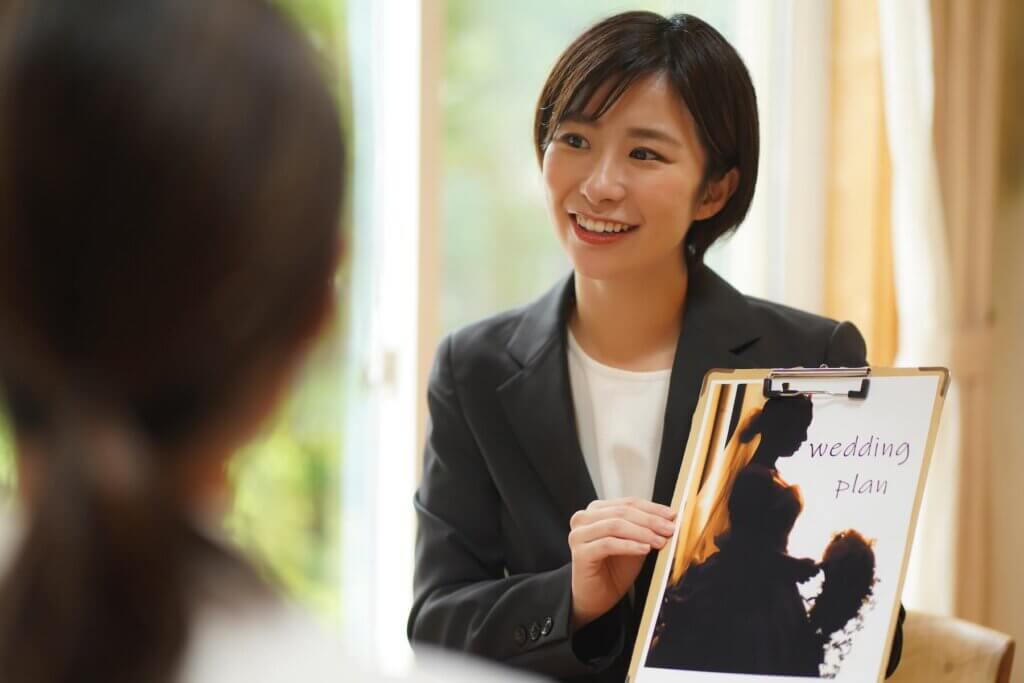 ウェディングプランをカップルに説明しているウエディングプランナー