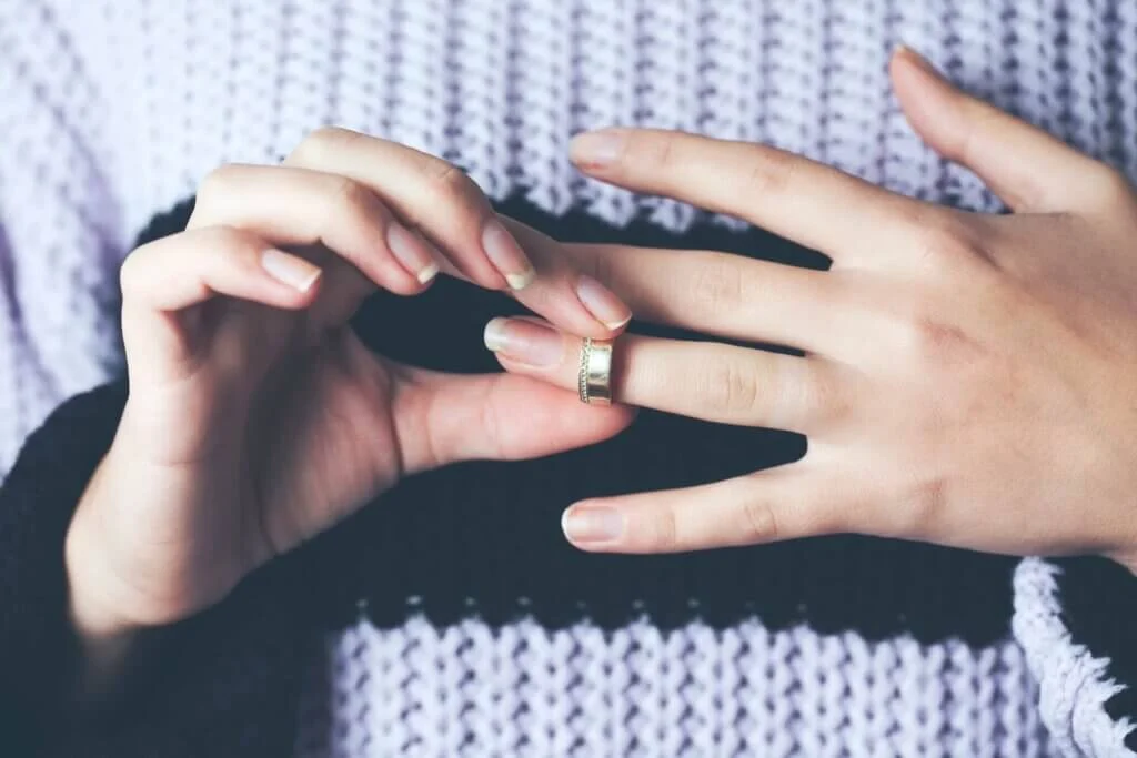 結婚指輪を左手の薬指に、自分自身ではめようとしている女性