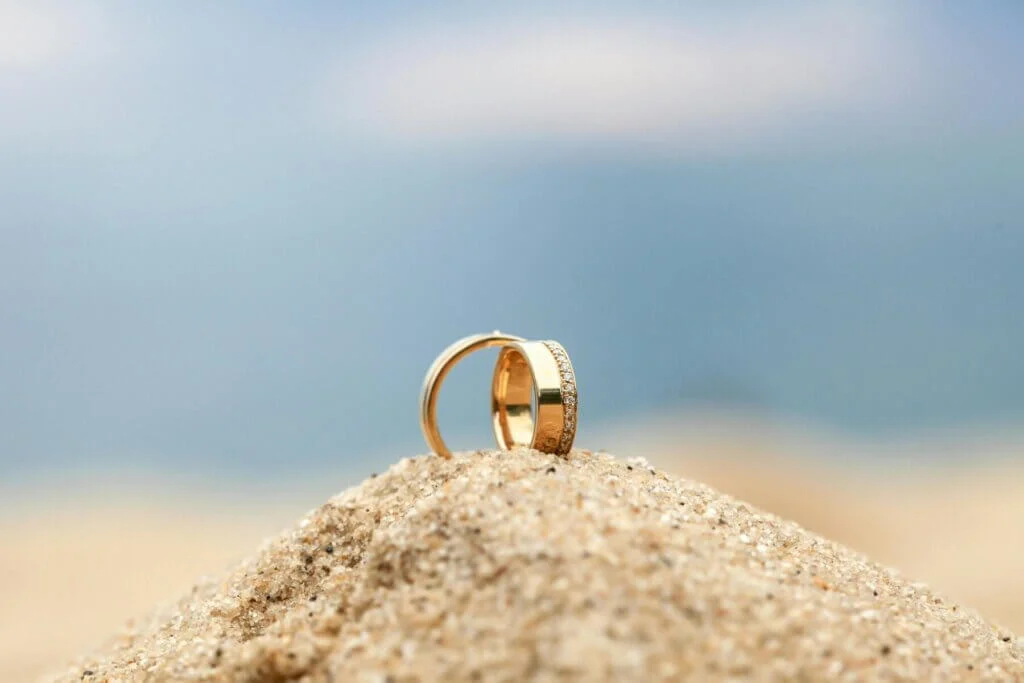 砂浜に置かれた金色のペアの結婚指輪