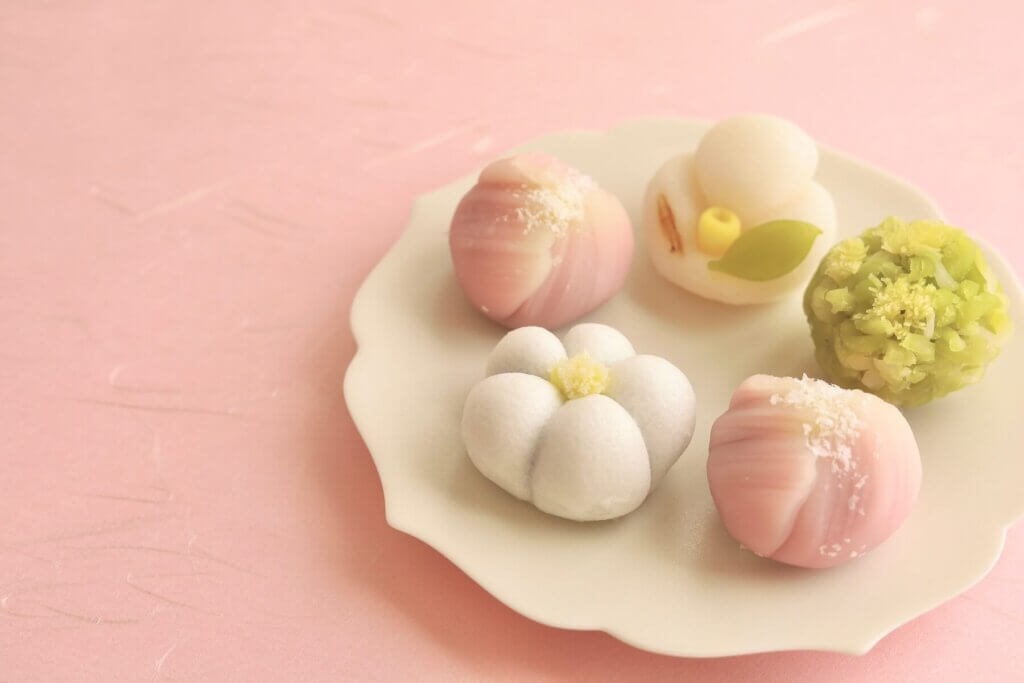 白やピンク、うぐいす色の丁寧に作られた小さな和菓子が白い小皿の上に5つ載せられている