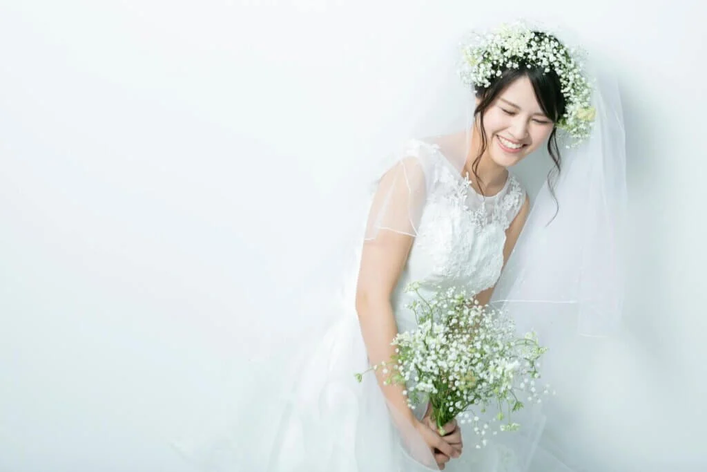 前かがみで、微笑んだポーズをとり、ウェディングドレスに身を包む新婦