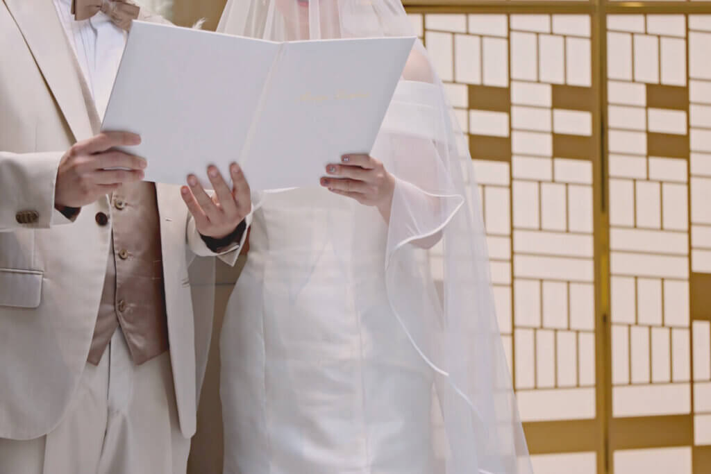 純白のウェディングドレスと白いタキシードに身を包み宣誓する新郎と新婦