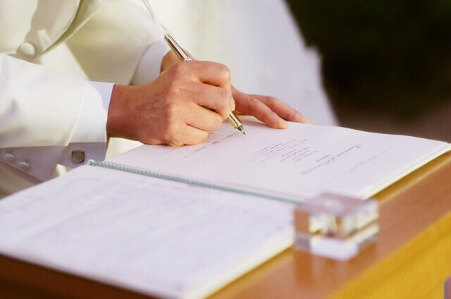結婚証明書にサインをしている白いタキシード姿の新郎