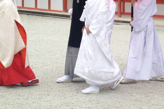 紋付袴と白無垢姿で、巫女さんの案内について神社を移動する新郎新婦