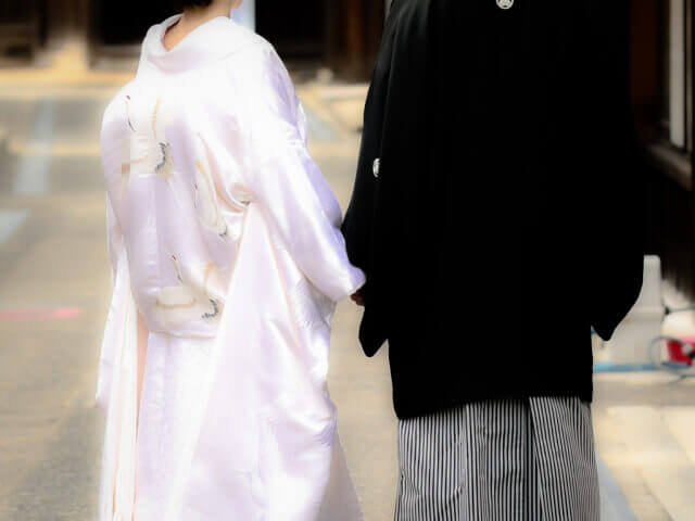 紋付袴と白無垢姿で神社に佇む新郎新婦