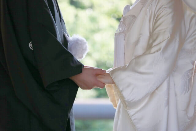 紋付袴と白組む姿で向かい合って手を取り合う新郎新婦