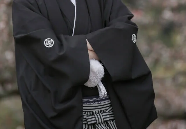紋付袴姿で腕を組む新郎