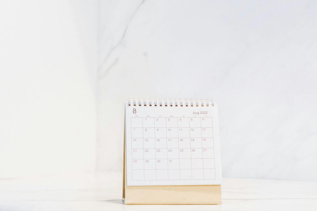 白いテーブルのに上に置かれたカレンダーが8月を表示している