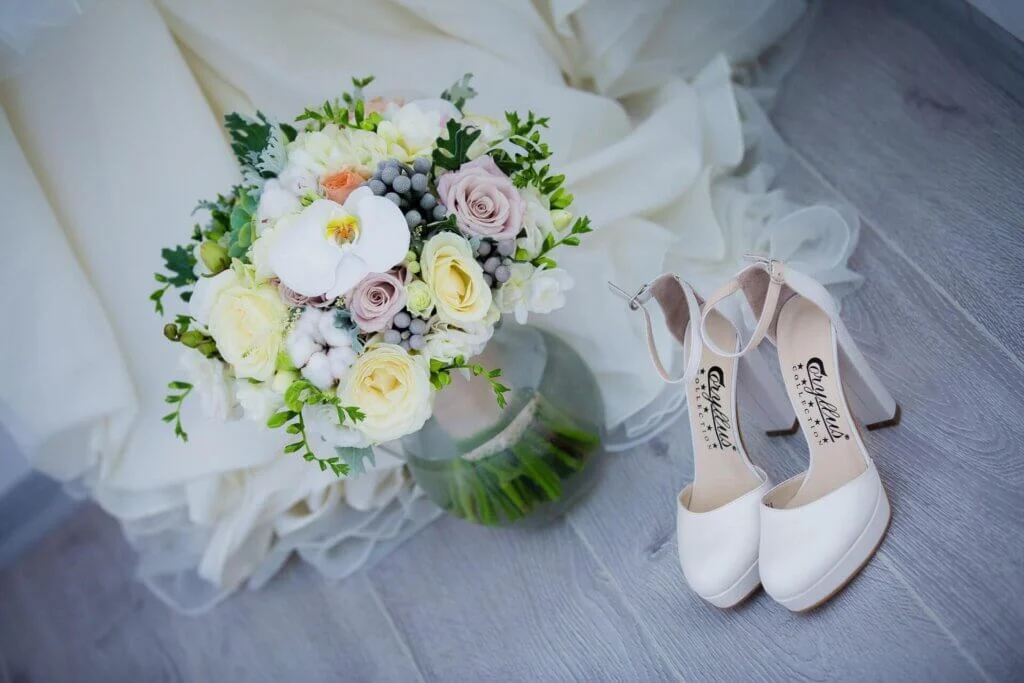 ウエーディングドレスの裾あたりに置かれたカラフルなブーケと白い新婦の靴