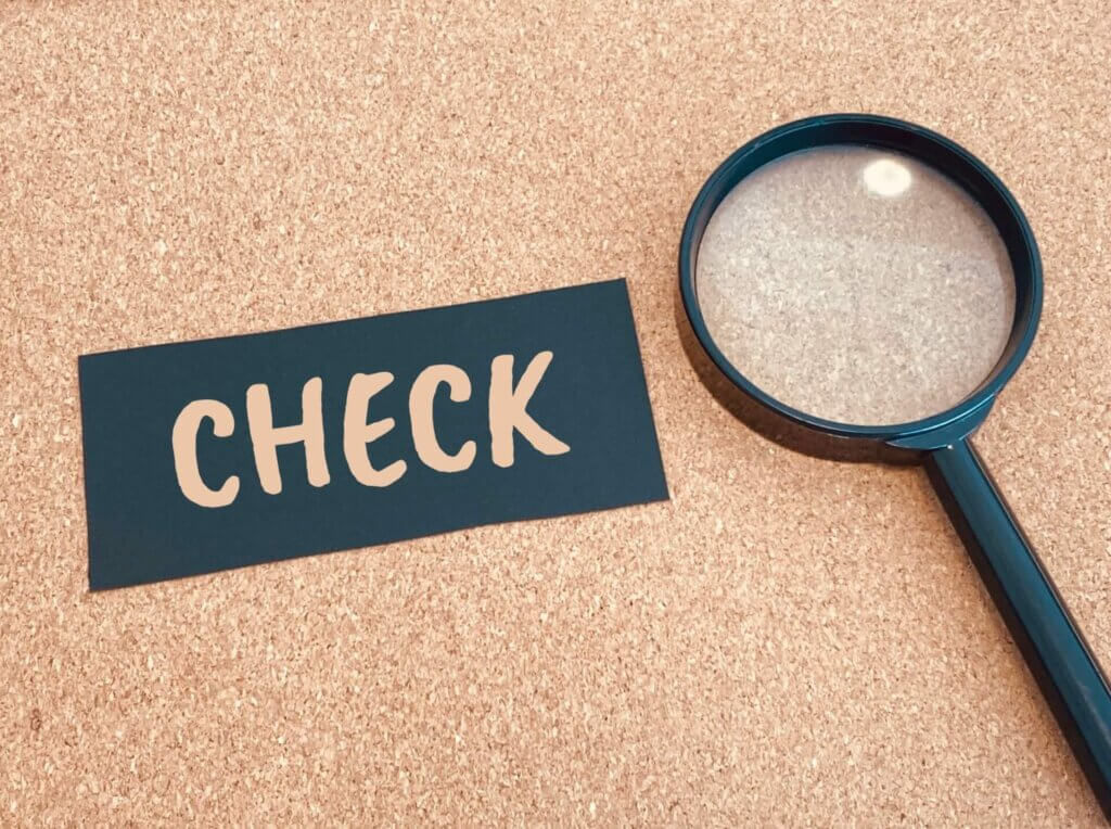 チェックと書かれた黒い紙の横に置かれている虫眼鏡