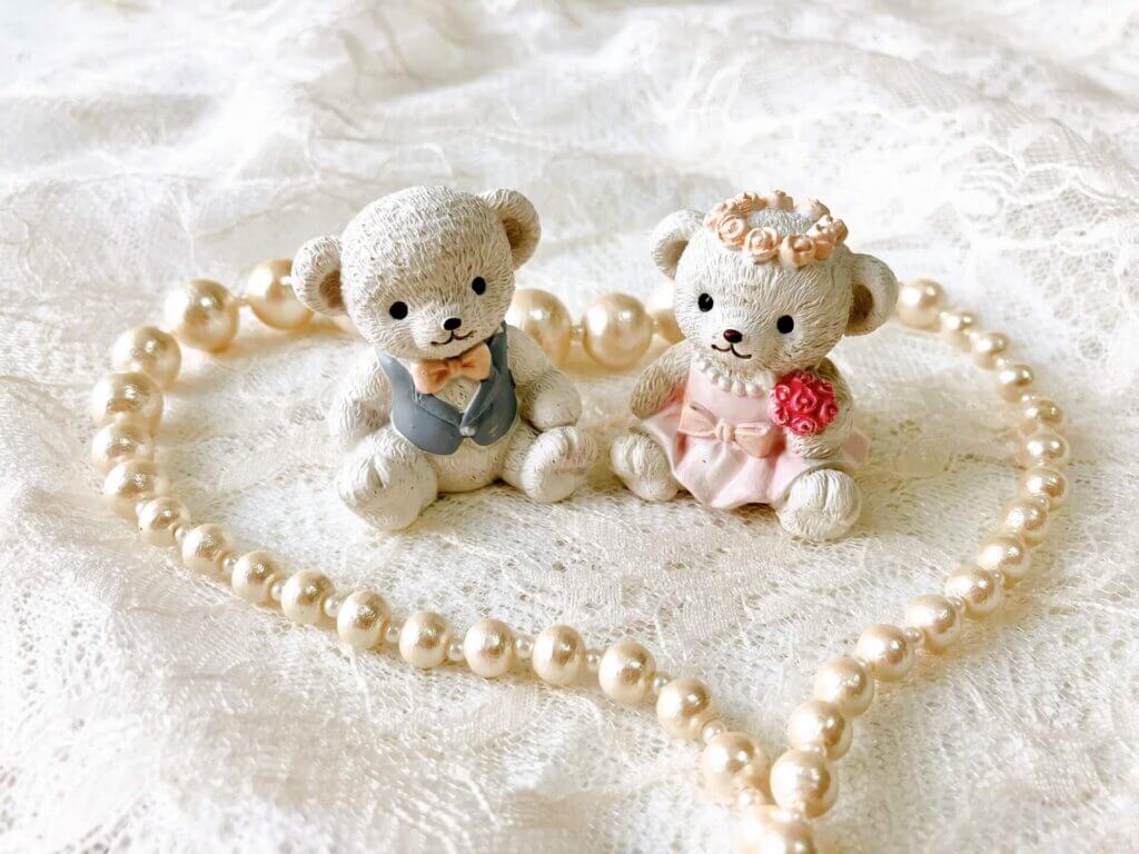 レースの上にハートを形取ったパールのネックレスが置かれて、その中に正装したホワイトベラーのぬいぐるみのセットが置かれている