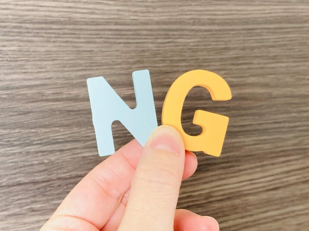 木製のNとGの文字を持つ左手